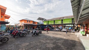 Cena de rua com motocicletas estacionadas, edifícios e algumas pessoas a pé.