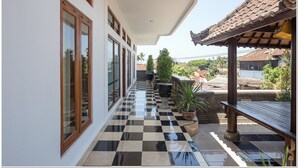 A covered outdoor corridor with checkered flooring, potted plants, and a wooden bench. - RedDoorz near Padang Galak Beach (Denpasar)