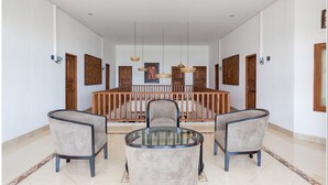 A spacious dining area with a high wooden railing, two upholstered chairs, and a glass-top table. - RedDoorz near Padang Galak Beach (Denpasar)