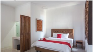 A hotel room with a large bed, a wooden partition, a small table, and a framed picture on the wall. - RedDoorz near Padang Galak Beach (Denpasar)