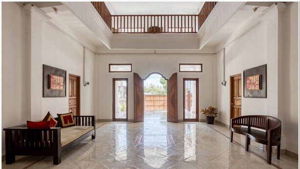 A spacious lobby with a high ceiling, a central open archway, and two wooden benches. - RedDoorz near Padang Galak Beach (Denpasar)