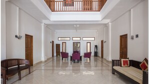 A spacious lobby with a high ceiling, a central seating area with chairs, a sofa, and a wooden bench. - RedDoorz near Padang Galak Beach (Denpasar)