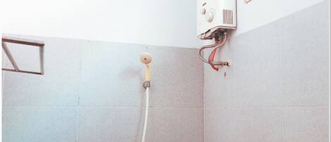 Un baño con ducha, paredes enlosadas y un enchufe a la vista.