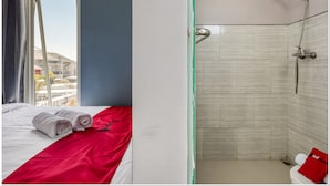 Une chambre d’hôtel avec un lit, une fenêtre et un espace douche.