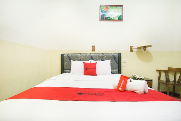 Una habitación de hotel con una cama, una mesita de noche, una lámpara y un cuadro en la pared.