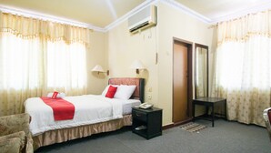 Ein Hotelzimmer mit Bett, Nachttisch, Lampe und Spiegel.
