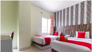Habitación de hotel con dos camas, un escritorio y una ventana con cortinas.
