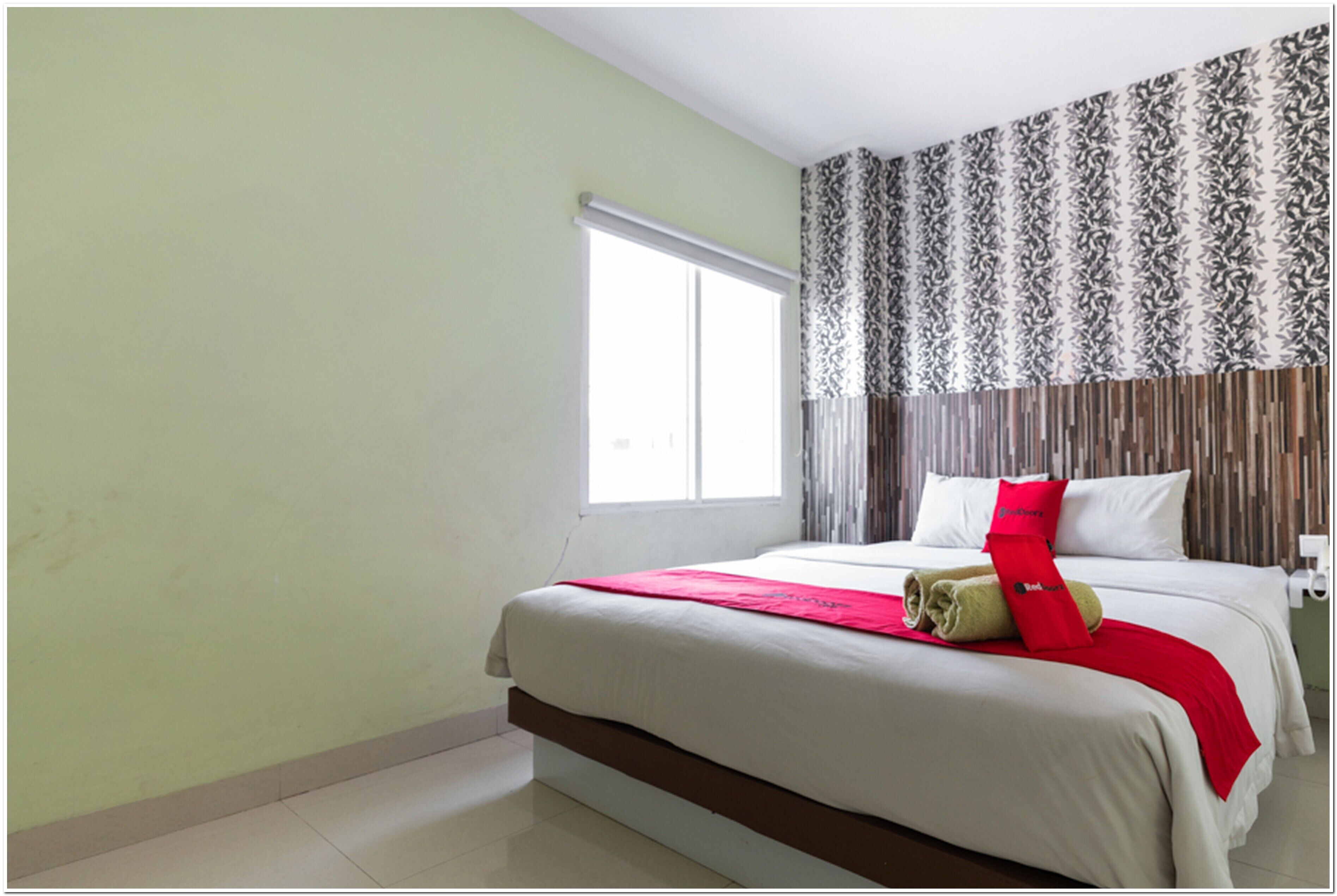 A hotel room with a large bed, a window with curtains, and a patterned wall.