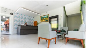 Un área de recepción con un escritorio moderno, dos sillones y un cuadro en la pared.