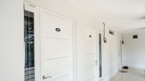 A hallway with white doors numbered 203 and 204, a tiled floor, and a small rug near the end.