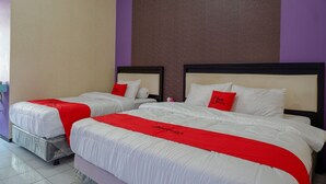 Hotellihuone, jossa on kaksi sänkyä. Kummassakin sängyssä on valkoiset vuodevaatteet ja punaiset yksityiskohdat, ja yhdellä seinällä on violetti tehosteväri.
