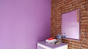 A bathroom with a purple wall, a white cabinet, and a mirror. - RedDoorz near RSUD Kebumen (Kebumen)
