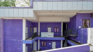 A multi-story building with purple walls and white trim. It features balconies, staircases, and a sign indicating it is a hotel. - RedDoorz near RSUD Kebumen (Kebumen)