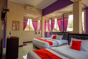 A hotel room with two beds, purple walls, and large windows with pink curtains. - RedDoorz near RSUD Kebumen (Kebumen)