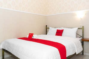 A neatly made bed with white and red bedding, a wooden headboard, and a wall-mounted light fixture.