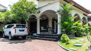 A house with a paved driveway, a white car parked in front, and a covered porch with chairs. - RedDoorz near Gajahmungkur Semarang (Semarang)