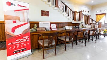 A reception area with a staircase, wooden furniture, and a RedDoorz advertisement.