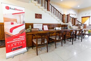 A reception area with a staircase, wooden furniture, and a RedDoorz advertisement. - RedDoorz Plus near Alun Alun Karanganyar (Karanganyar)
