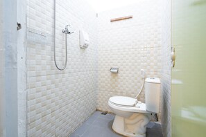A small, tiled bathroom with a toilet, a shower, and a hand dryer. - RedDoorz near Exit Toll Tanah Baru Bogor (Bogor)