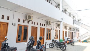 A building with multiple air conditioning units, wooden doors, and a staircase. - Formerly Reddoorz Syariah Jatisampurna Hospital (Bekasi)