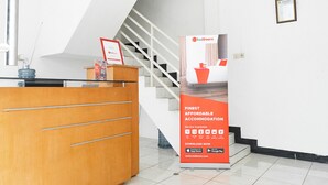 A reception desk with a sign for RedDoorz, a staircase, and a framed certificate on the wall. - Formerly Reddoorz Syariah Jatisampurna Hospital (Bekasi)