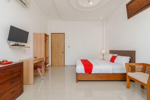 A hotel room with a bed, a desk with a chair, a television, and a wardrobe. - RedDoorz Syariah near Lahat Station (Lahat)