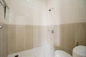 A bathroom with a toilet, a shower, and a mirror. - RedDoorz Syariah near Lahat Station (Lahat)