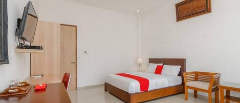 Quarto de hotel com cama de madeira, escrivaninha e televisão.