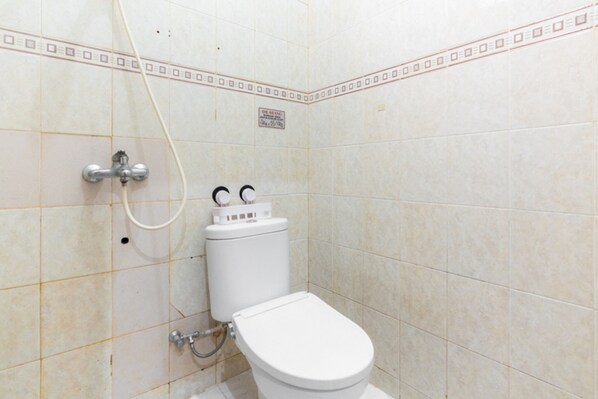 A small, tiled bathroom with a toilet, a shower, and a hand dryer. - RedDoorz @ Pengayoman Panakkukang 3 (Makassar)