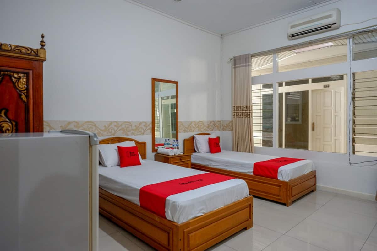 A hotel room with two beds, a mirror, and a window with curtains.