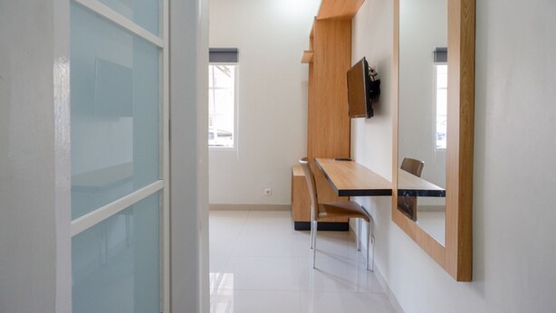 A modern, minimalist room with a wooden desk, a chair, and a mounted TV. - RedDoorz Syariah near Mutiara SIS Al Jufrie Airport Palu 2 (Palu)