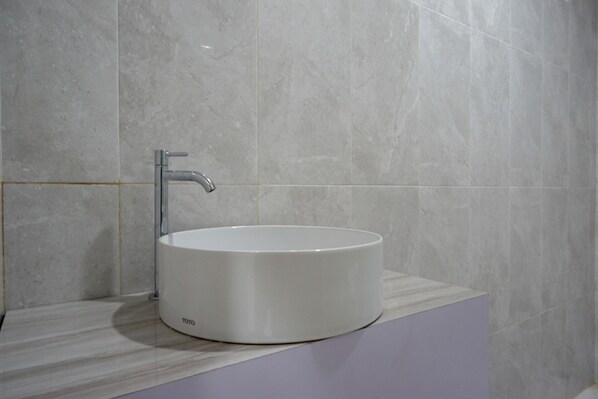 A modern bathroom with a round white sink, a chrome faucet, and a marble countertop. - RedDoorz Syariah near Mutiara SIS Al Jufrie Airport Palu 2 (Palu)
