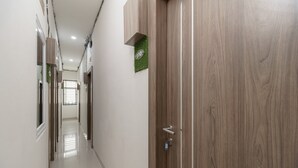 Un pasillo con una puerta de madera, un cartel con un número y una señal verde montada en la pared.