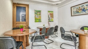 A conference room with a wooden table, black chairs, a potted plant, and a poster on the wall. - Formerly Reddoorz Hostel @ Feliz Noche Cengkareng (Jakarta)
