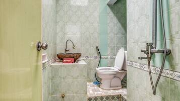 A bathroom with a toilet, a sink with a decorative bowl, and a shower area.