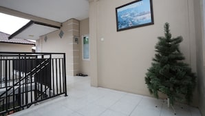 Un espace intérieur spacieux avec un escalier, un tableau encadré au mur et un petit arbre artificiel.