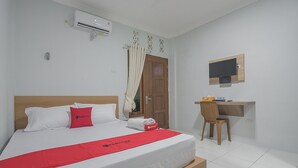 Hotellihuone, jossa on sänky, työpöytä, tuoli, televisio ja ilmastointilaite.