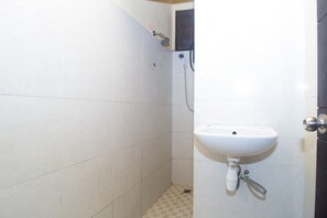 Un baño pequeño con azulejos blancos, un lavabo y una ducha.