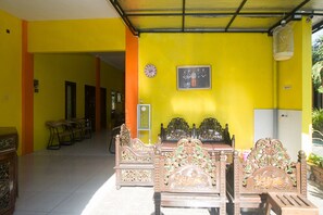Una habitación con pared amarilla, cama con cabecero decorado y un reloj.