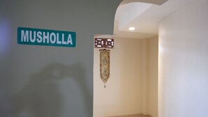 Ein Flur mit einem Schild, auf dem 'MUSHOLLA' steht, und einem dekorativen Wandbehang.