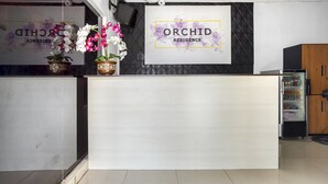 A reception desk with a sign reading "ORCHID RESIDENCE" and potted orchids. - RedDoorz near Tomang 2 (Jakarta)