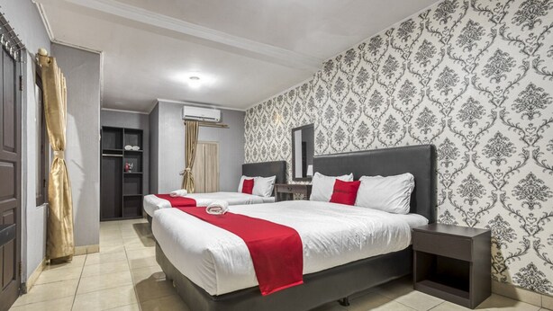 A hotel room with two beds, a wardrobe, a vanity, and a mirror. - RedDoorz near Tomang 2 (Jakarta)