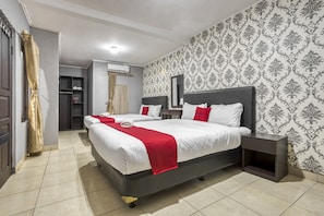 A hotel room with two beds, a wardrobe, a vanity, and a mirror. - RedDoorz near Tomang 2 (Jakarta)