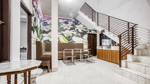 A modern interior with a marble dining table, a sofa, a kitchen area, and a staircase. - RedDoorz near Tomang 2 (Jakarta)