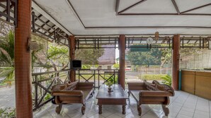 Un área de estar al aire libre cubierta con mobiliario de madera y piso de baldosas.