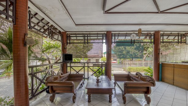 Un área de estar al aire libre cubierta con mobiliario de madera y piso de baldosas.