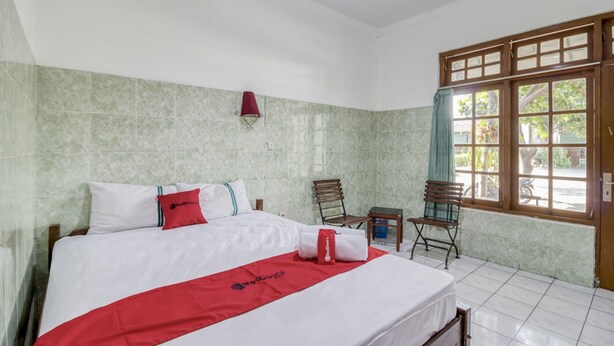 Habitación de hotel con cama, escritorio, silla y ventana con vista al exterior.