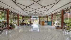 Un amplio espacio interior con suelo de baldosas, muebles de madera y plantas en macetas.
