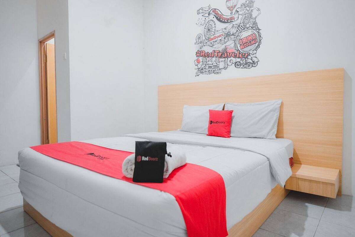 A hotel room with a bed, a RedDoorz towel, and a wall decal.
