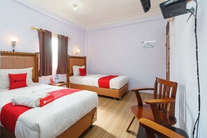 A hotel room with two beds, a wooden chair, a desk, and a television.